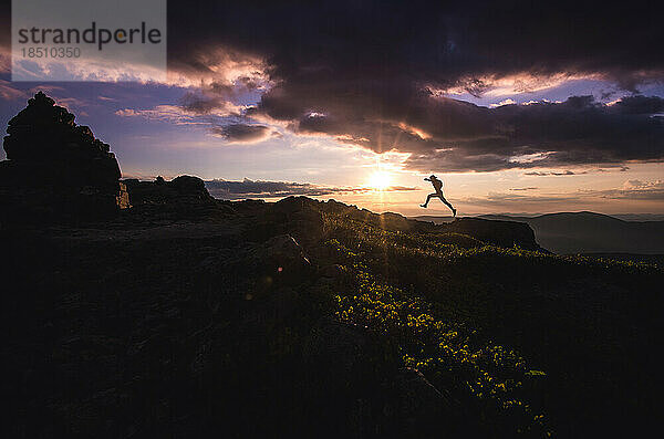 Silhouette eines Trailrunners  der zwischen Felsen springt