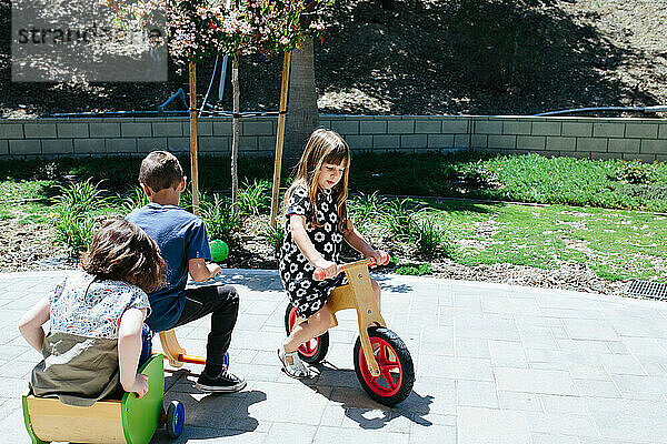 Draußen spielen Kinder auf Holzfahrrädern