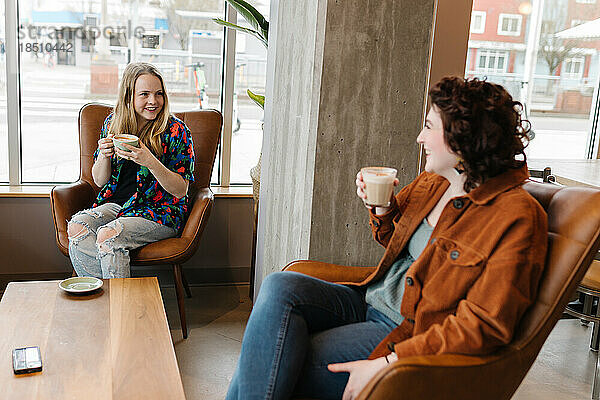Zwei junge Frauen lachen zusammen im Café