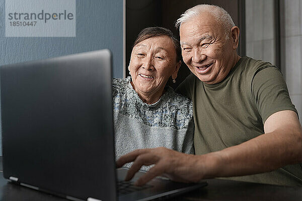 Ruhiges Seniorenpaar zu Hause nutzt Laptop zum Online-Shopping