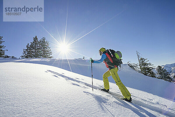 Skifahrer klettert auf schneebedeckten Berg