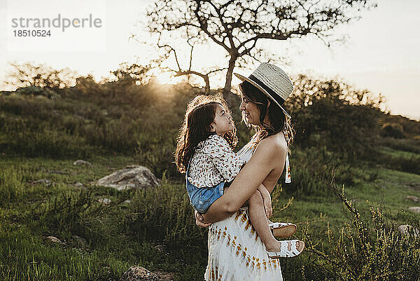 Side view of mother holding daughter while looking at each other