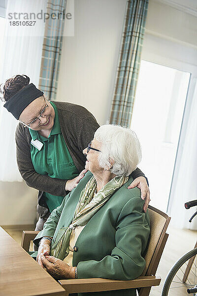 Pflegepersonal  das sich um eine ältere Frau im Altersheim kümmert