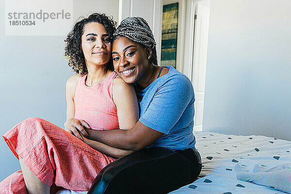 Porträt selbstbewusster  glücklicher Lesben  die zu Hause im Bett sitzen