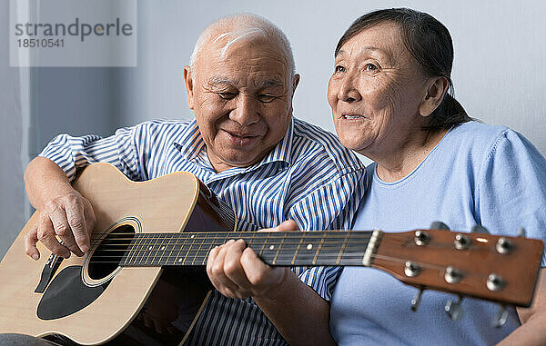 Älterer Mann spielt Akustikgitarre und singt mit seiner Frau