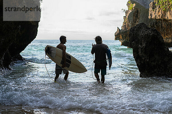 Mann mit Surfbrett geht zum Surfspot Uluwatu.