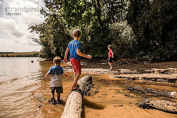 Drei Jungen spielen an einem sonnigen Tag im und um den See