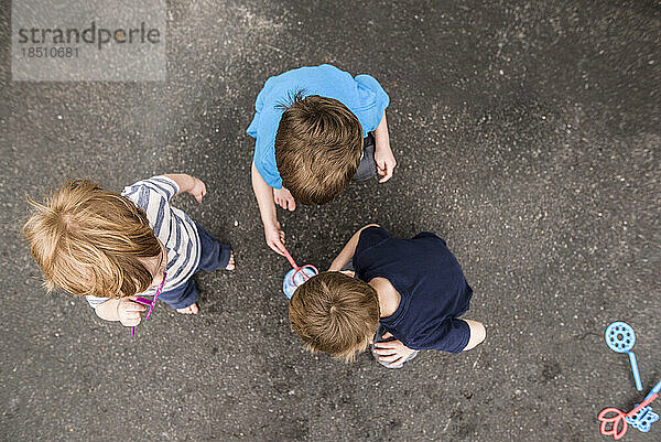 Blick auf drei Jungs  die draußen mit Seifenblasen spielen