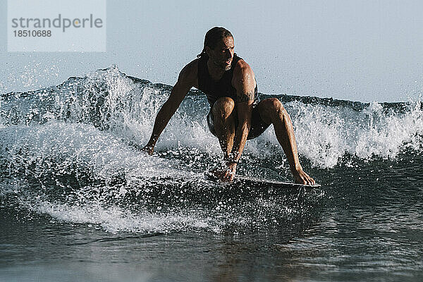 Ganzkörper eines männlichen Surfers im Meer bei Sonnenuntergang