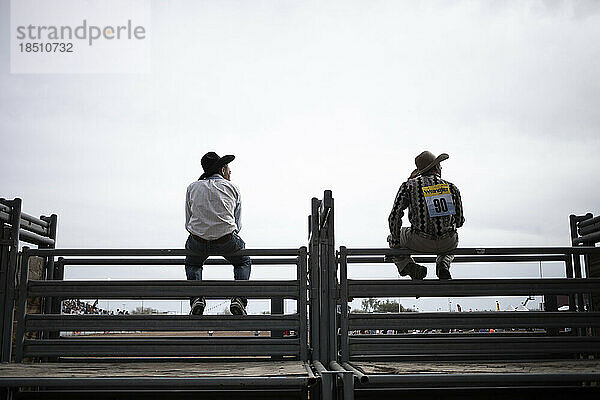 Cowboys sitzen auf einem Zaun beim Arizona Black Rodeo