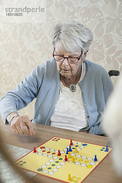Ältere Frau spielt Ludo-Brettspiel im Pflegeheim
