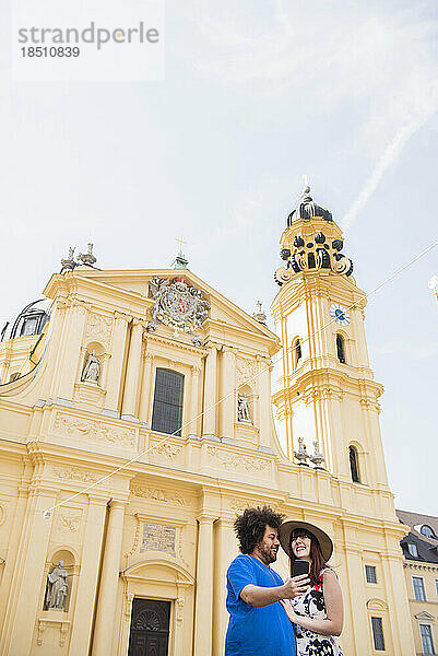 Paar macht Selfie mit Handykamera vor der Theatinerkirche  München  Deutschland