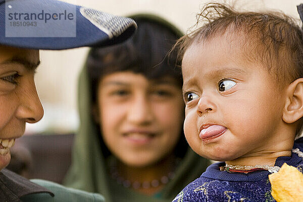 A baby sticks out its tongue at another child in Kabul.