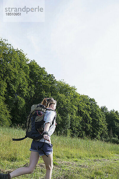 Junge Frau läuft mit Rucksack in einem Wald  Bayern  Deutschland