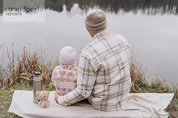 Vater und kleine Tochter verbringen gemeinsame Zeit in der Nähe eines ruhigen Flusses