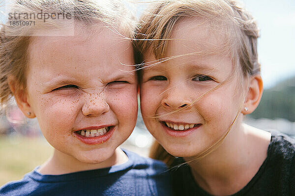 Zwei Mädchen lächeln glücklich mit allen Gesichtern im Rahmen und Wind im Haar