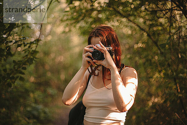 Frau fotografiert mit Kamera im Wald