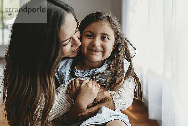 Porträt eines 5-jährigen Mädchens  das lächelt  während die Mutter sie umarmt