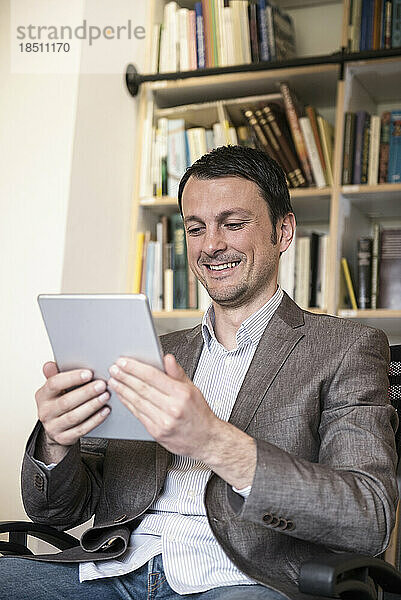 Reifer Geschäftsmann nutzt digitales Tablet in einem Büro und lächelt  Bayern  Deutschland