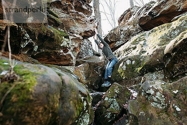 Kind klettert bei Waldwanderung auf Felsbrocken