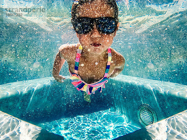 Mädchen schwimmt unter Wasser mit Sonnenbrille