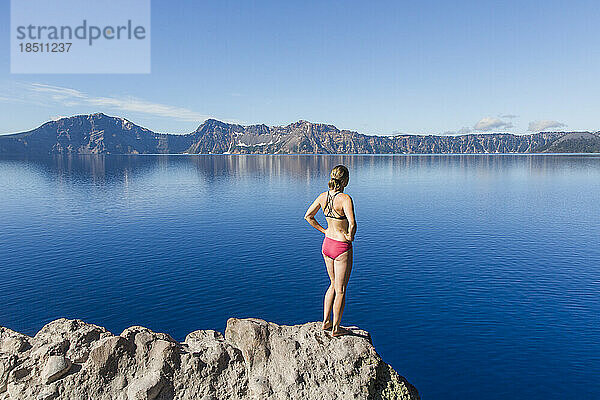 Eine junge Frau steht am Rand des Kratersees.