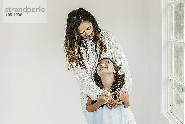 Mother and daughter looking at each other in natural light studio
