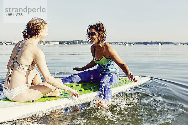 Zwei junge Frauen vergnügen sich auf einem Standup-Paddle-Board