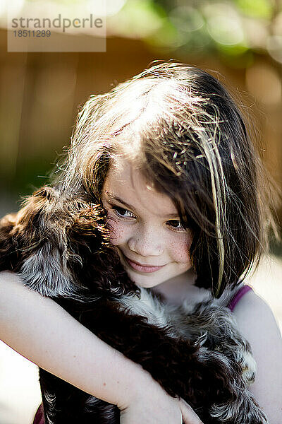 Achtjähriges Mädchen hält und umarmt Welpen in San Diego