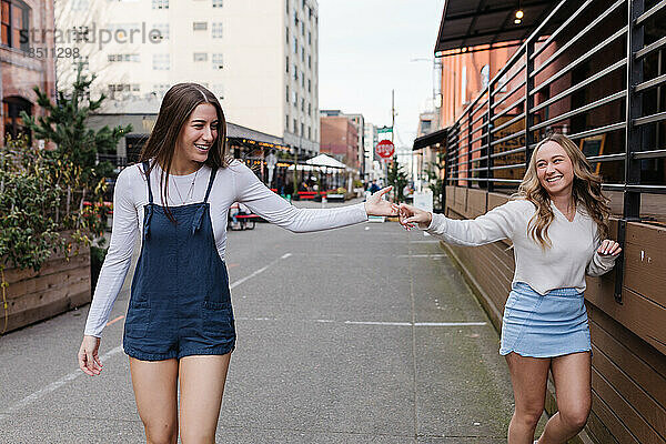 Zwei Frauen halten Händchen und lachen gemeinsam in der Innenstadt
