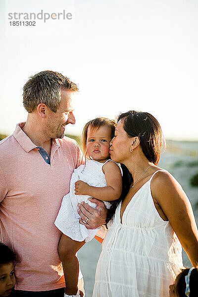 Vater hält Kleinkind und Mutter küssen sich am Coronado Beach in San Diego