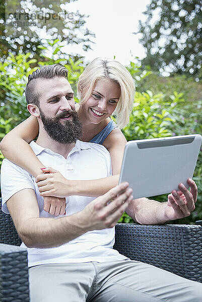 Glückliches junges Paar macht ein Selfie mit einem digitalen Tablet im Garten  Bayern  Deutschland