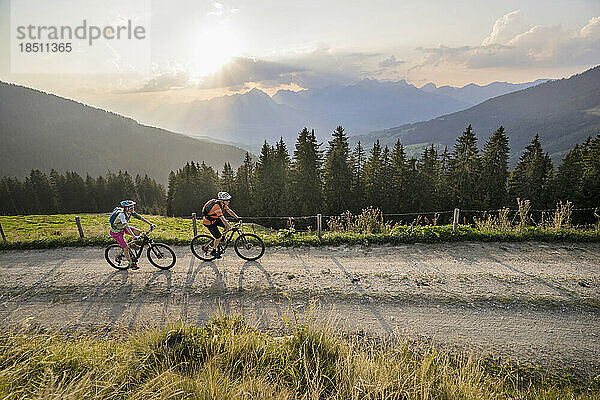 Erhöhter Blick auf Mountainbiker  die bei Sonnenuntergang auf einer unbefestigten Straße fahren  Zillertal  Tirol  Österreich
