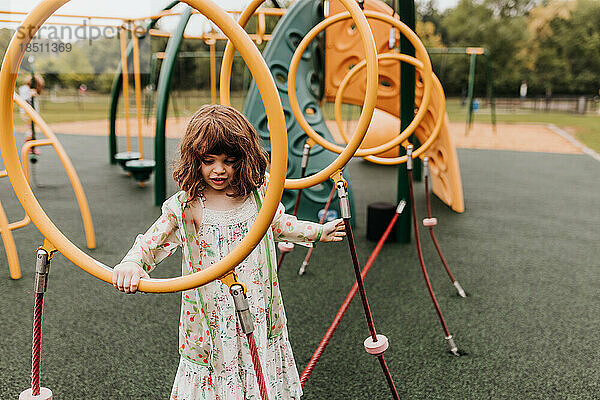 Junges Mädchen spielt an bewölktem Tag auf Spielgeräten im Park