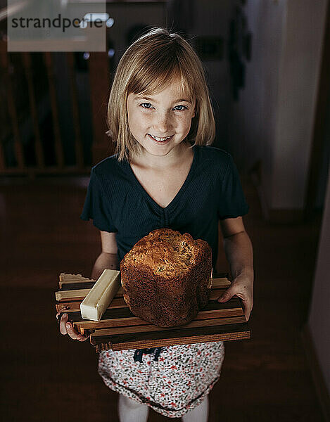 Junges Mädchen hält einen Laib selbstgebackenes Brot