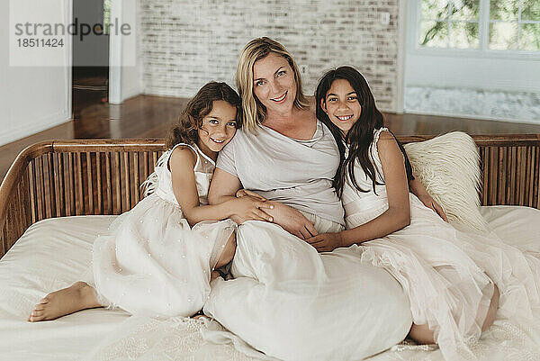 Porträt einer Mutter und zweier Töchter auf der Couch im Studio mit natürlichem Licht