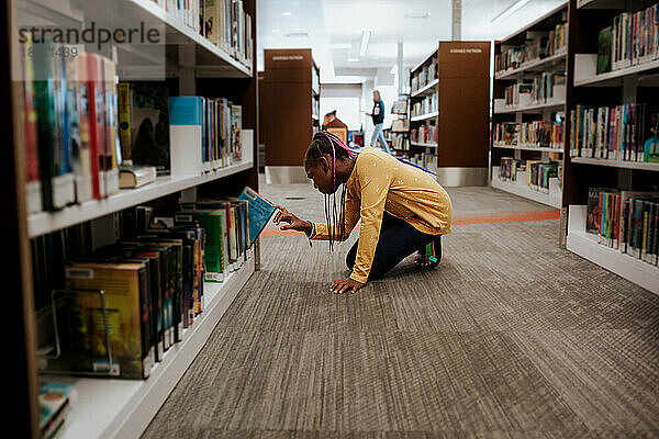 Young girl choosing book in library