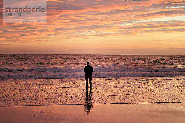 Mann beobachtet das Meer bei Sonnenaufgang