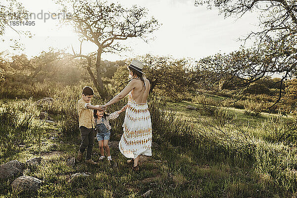 Schöne Mutter und kleine Kinder spielen im sonnigen Feld