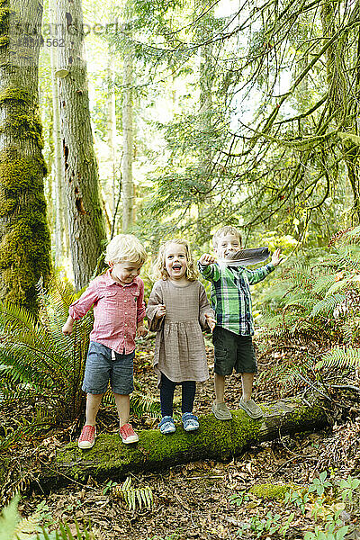 Geradeaus Porträt von drei Kindern  die zusammen im Wald spielen