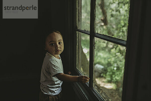 Young boy next to large window looking at camera