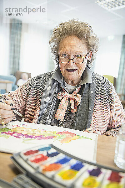 Ältere Frau malt Obst mit Wasserfarbe