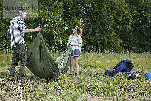 Junges Paar packt sein Zelt zusammen  Bayern  Deutschland
