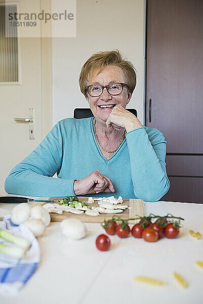 Alte Frau am Küchentisch bereitet Essen zu