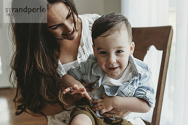 Nahaufnahme eines kleinen Jungen im Vorschulalter  der von seiner Mutter im Studio umarmt wird