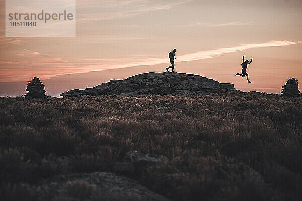 Silhouette männlicher Trailrunner  die bei Sonnenaufgang über den Bergrücken laufen