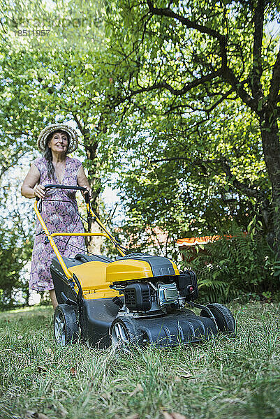 Ältere Frau mäht den Rasen in einem Garten  Altötting  Bayern  Deutschland