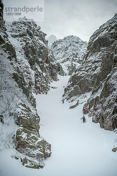 Skifahrer erklimmen beim Backcountry-Skifahren eine verschneite Schlucht