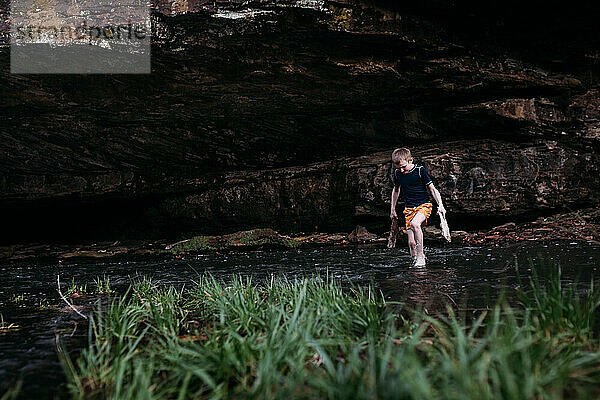 Kind überquert Bach unter einer Steilküste