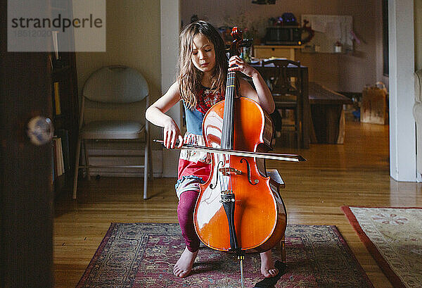 Ein junges barfüßiges Mädchen spielt leidenschaftlich und mit geschlossenen Augen Cello